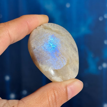 Person holding a stone with a blue flash against a blue gradient background